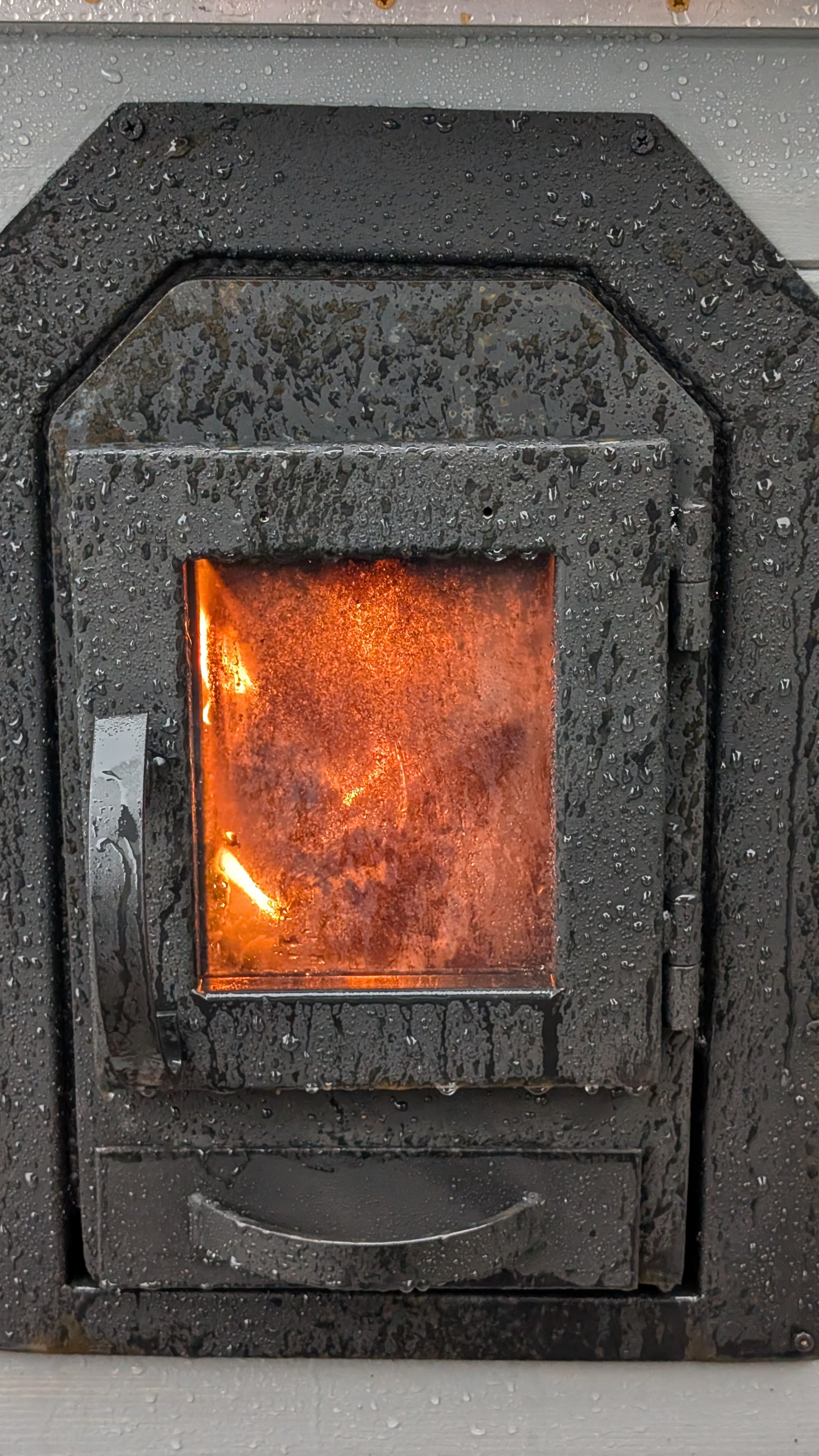 Close-up of wood-fired sauna stove with fire